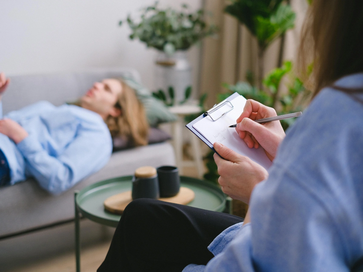 GT Sessions Therapist taking notes while client lies on couch during psychodynamic therapy session